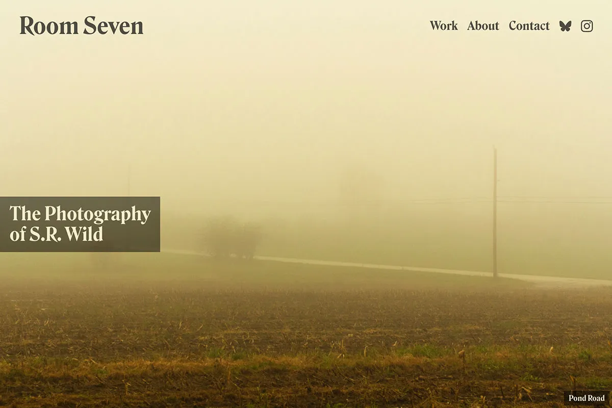 Screenshot of a web site with Room Seven in the upper left corner and a navigation to the right of it. In the middle-right is a large headline, The Photography of S.R. Wild. There’s an image that fills the screen of a yellow tinted photography looking across a field, bisected by a road with telephone poles that disappear into the fog.